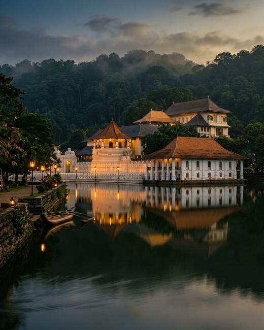 The Temple of the Sacred Tooth Relic reflected in Kandy Lake at dusk